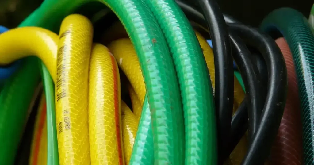 Hiverner son arrosage : tuyau d'arrosage vert, jaune et noir enroulé et rangé à l'abri du gel avant l'hiver